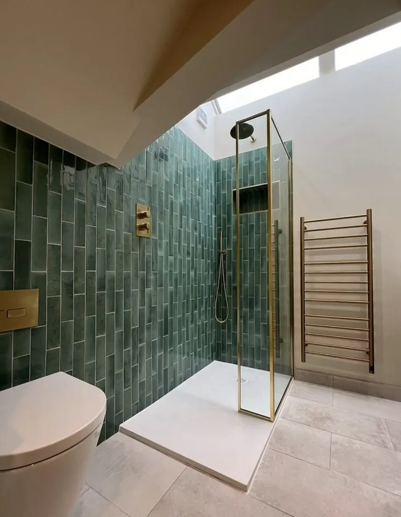 Shower room with green metro tiling, a brass-framed shower enclosure, brass ladder radiator and a skylight above